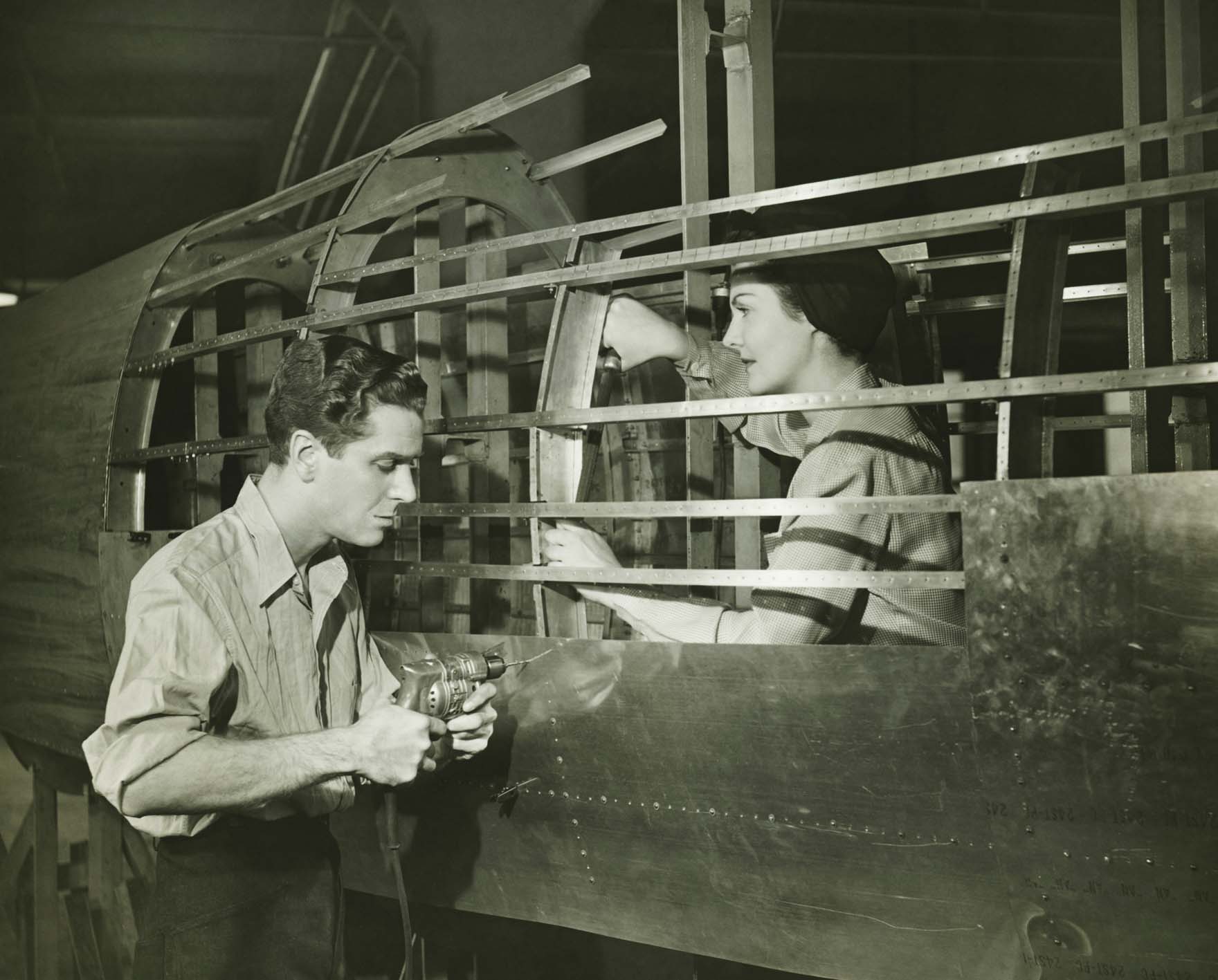 World War II photo: Young man and woman working in plane body in factory