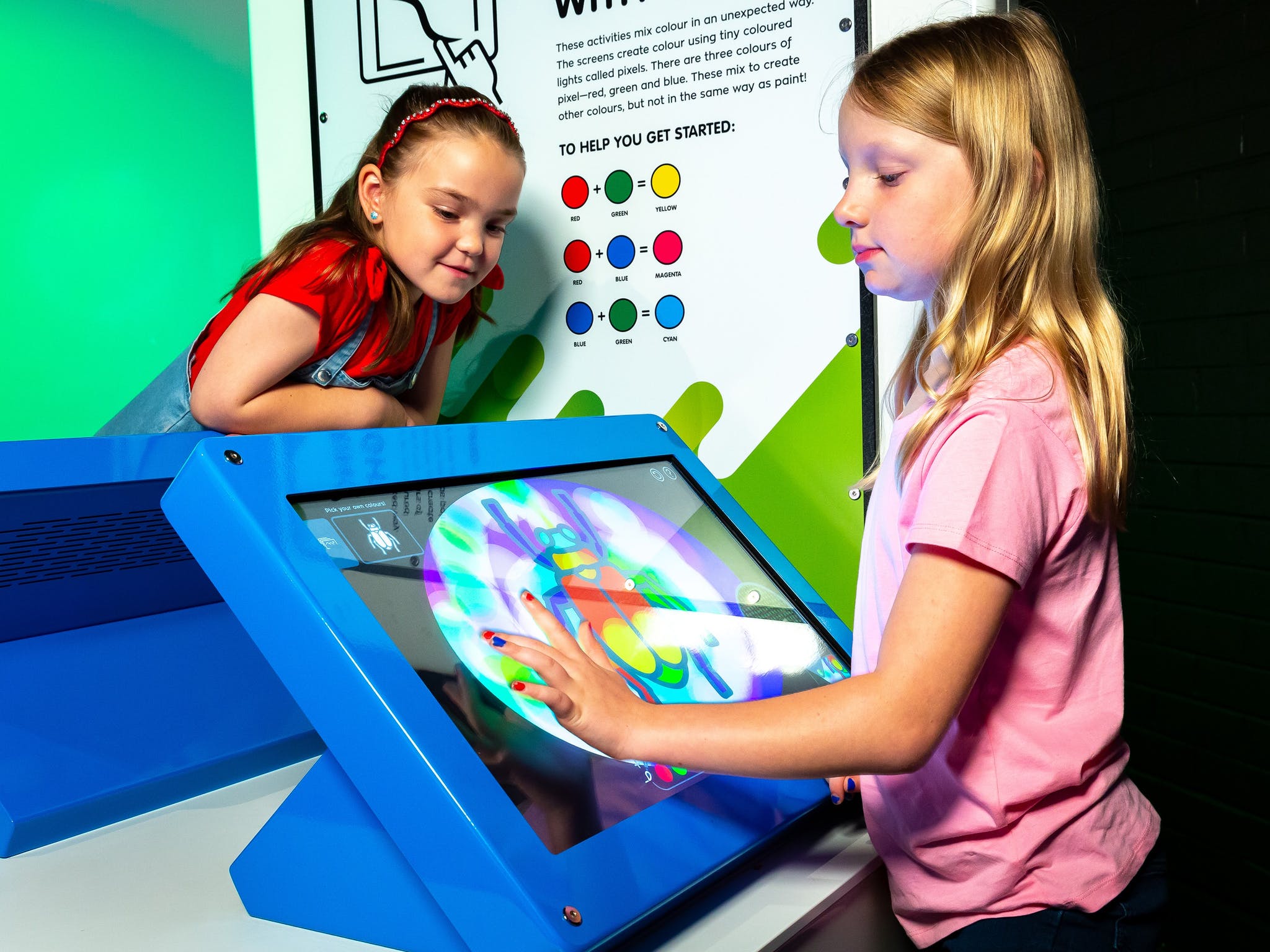 A girl mixes virtual colours on an electronic touch screen in the an exhibit kiosk A girl mixes virtual colours on an electronic touch screen in the an exhibit kiosk