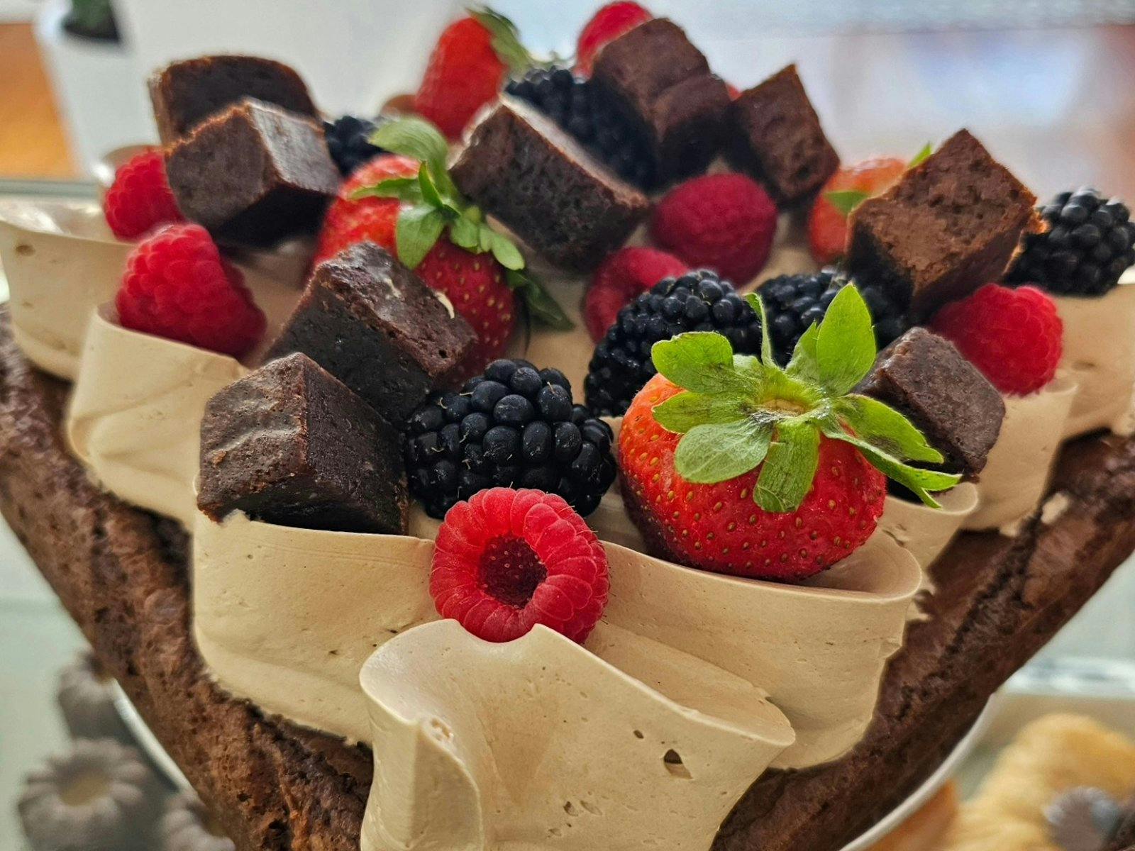 Brownie cake with icing brownie pieces and berries on top Brownie cake with icing brownie pieces and berries on top