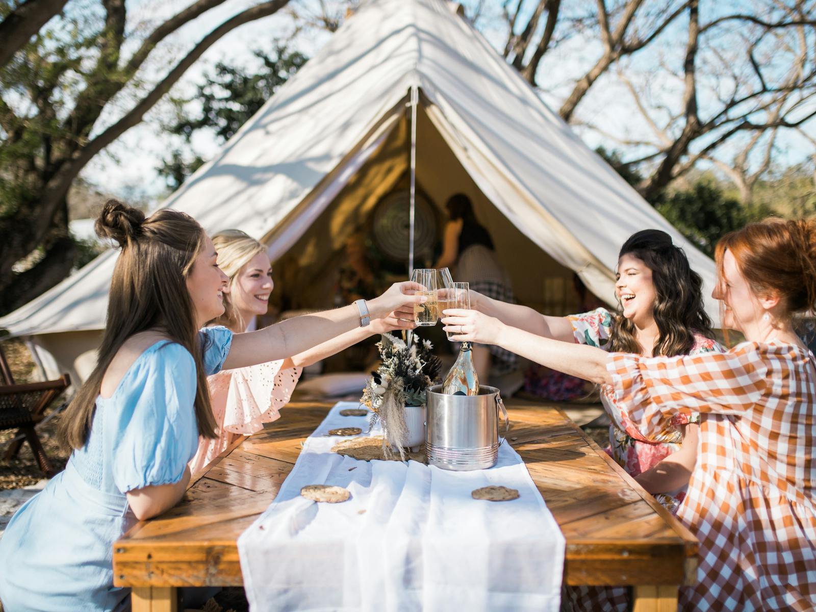 Four girlfriends celebrating ain front of Soul Nook's bespoke Bell Tent Picnic.
